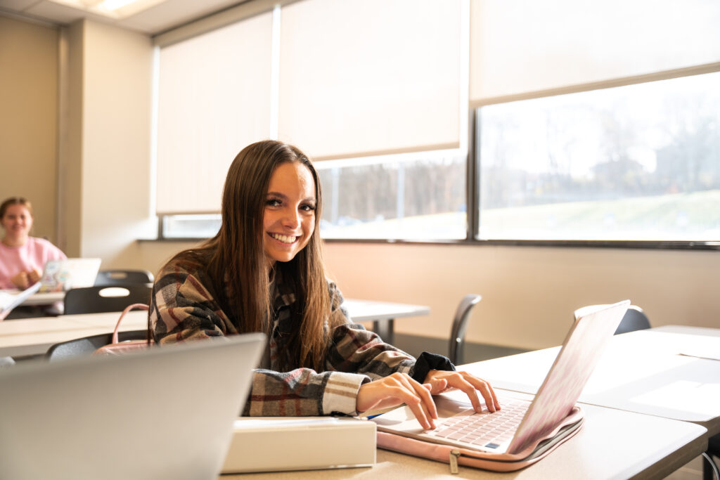 ccbc female student typing on her laptop in a classroom